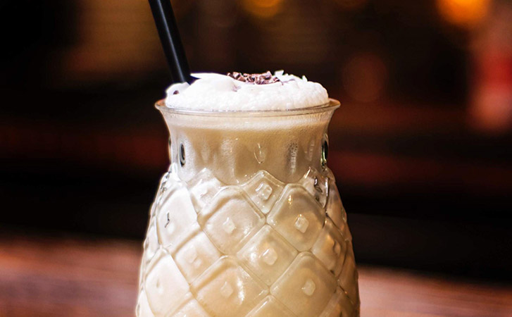 The Bushwacker drink in a pineapple glass with a straw