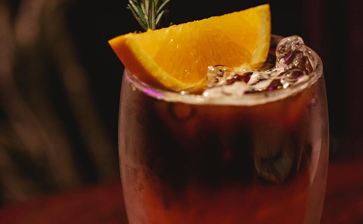 A cold brew bourbon in a glass with an orange on top