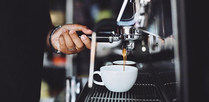 A person pulls a double shot of espresso from an espresso maker