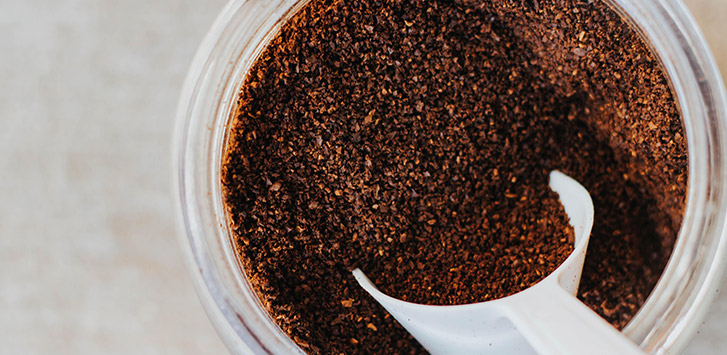 Looking down on an open glass jar full of coffee grounds
