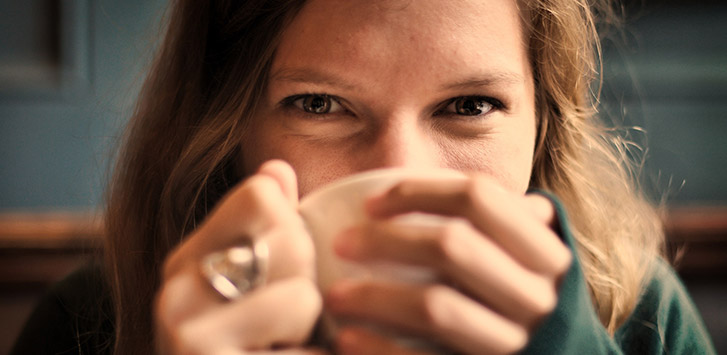 Woman drinking coffee and smiling at the camera